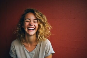 Portrait of a glad woman in her 20s laughing on plain cyclorama studio wall