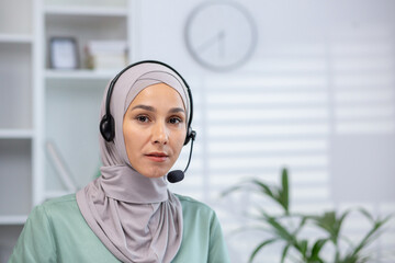 Confident woman in hijab working as customer support representative, using a headset at a modern...