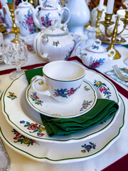 Close-up of a beautifully arranged vintage floral porcelain dinnerware set, featuring intricate flower patterns and a green napkin, perfect for elegant dining settings.