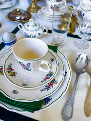 Close-up of a beautifully arranged vintage floral porcelain dinnerware set, featuring intricate flower patterns and a green napkin, perfect for elegant dining settings.