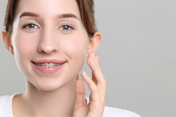 Obraz premium Portrait of smiling woman with dental braces on grey background. Space for text