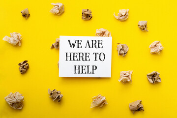 A yellow background with a white sign that says We are here to help