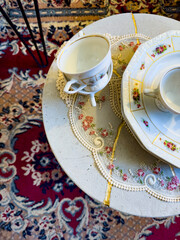 Elegant vintage tea set displayed on a lace-covered table with a colorful oriental rug in the background. Ideal for projects focused on home decor, vintage collections, and traditional aesthetics.