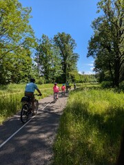 View of Via Rhona with distant cyclists, beautiful spring day with blue sky and lush nature,...
