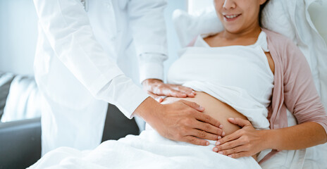 Obraz premium parent, parenthood, mother, pregnancy, motherhood, birth, pregnant, abdomen, tummy, anticipation. A woman is laying with doctor touching her stomach. doctor is checking on the baby inside.