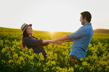 Couple, dance and sunset with field of flowers with care, love and bonding for memory on travel in countryside. Man, woman and vacation with holding hands, connection and floral plants in spring