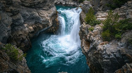 High-angle shot of a majestic waterfall, water flowing rapidly over the rocks into a serene pool below.