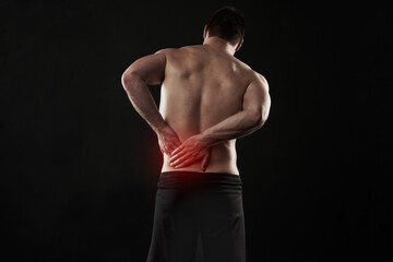Fototapeta premium Back pain, injury and red glow with man on black background for accident, anatomy or emergency. Fitness, healthcare and medical with shirtless athlete holding sore or stiff muscle in discomfort