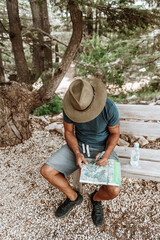 Man Tourist Looks at Maps in Forest.