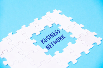 A white puzzle piece with the word business network written in blue
