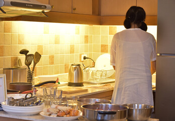 Real back view of housewife standing alone in kitchen for preparation supper, Selective focus.