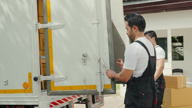 Delivery men unload cardboard boxes from a truck. Movers in uniform work together showcasing teamwork in a relocation service. Smiling workers carrying orders. relocation teamwork Moving Day