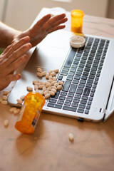 Obraz premium Person with addiction taking pills over his laptop with many pills around, desesperate