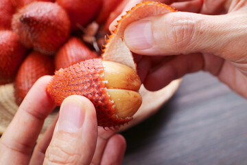 Closeup of Hand Peeling Salak Fruit by Pinching Its Tip and Pulling Away