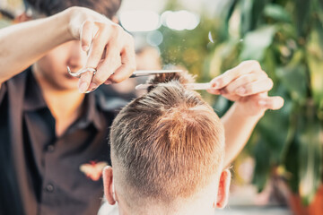 Neat young Vietnamese hairdresser makes haircut to male. Back view. Professional skills © NOVOZHILOV ANDREI