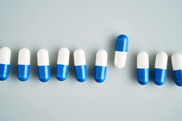 A row of white and blue pills on a blue background.