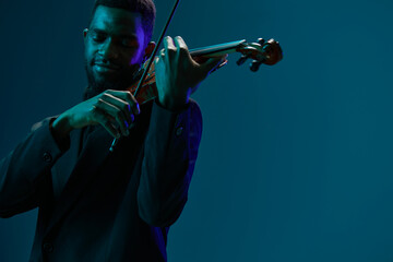 Elegant musician in formal attire playing the violin with passion on a vibrant blue background