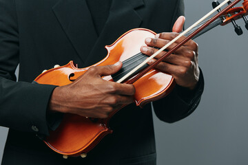 Closeup portrait of a man in a suit playing a violin in front of a gray background