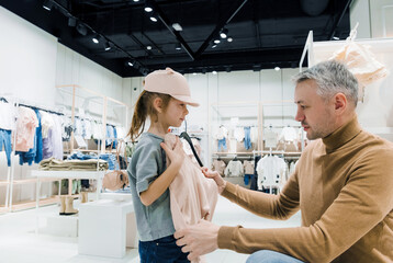 Father Helping Daughter Try on Clothes in Modern Clothing Store During Afternoon