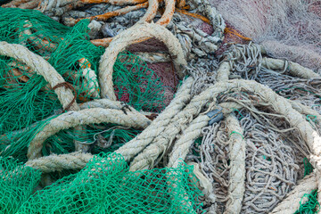 There is a large pile of fishing nets lying on the wooden pier to dry.