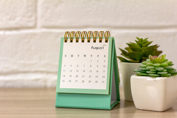 Desktop calendar for August 2024. Monthly planning calendar and vase with dried flowers on the...
