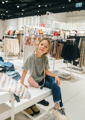 Young Girl Enjoying Shopping at a Chic Clothing Store in Daytime