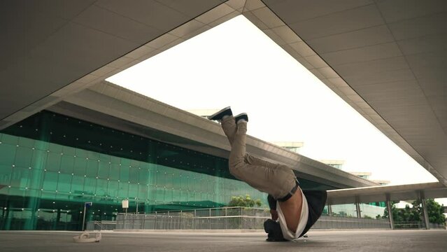 Happy hipster practice b boy dance with stylish cloth at building. Skilled street dancer enjoy show footstep performance. Modern lifestyle, break dancing. Slow motion. Outdoor sport 2024. Sprightly.