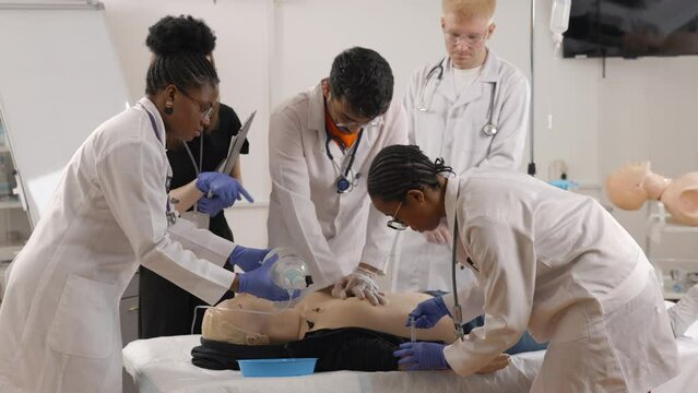 Group of people learning how to make first aid heart compressions with dummies during the training