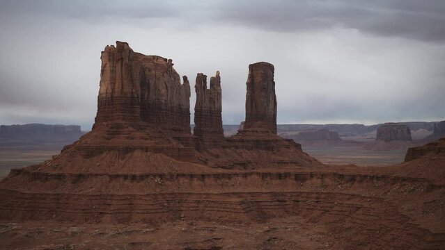 Aerial flyover panning shot of Bear and Rabbit and King on his Throne rock formations / Monument Valley, Utah, United States