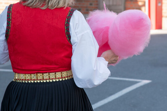 Person in bunad holding pink cotton candy 