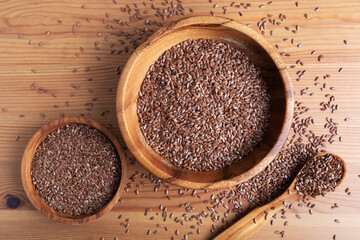 Wooden bowl of organic flaxseed or linseed on rustic table top view.