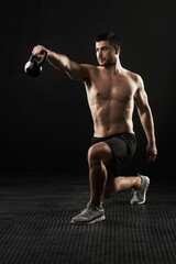Muscular man, weightlifting and fitness with kettlebell in squat for workout or exercise on a black...