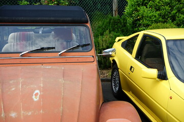 Kleinwagen in Orange neben einem Sportwagen und Coupés in Gelb aus dem Frankreich der Siebziger...