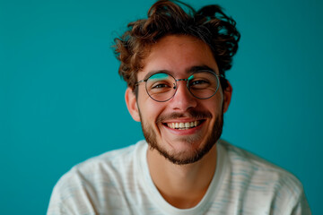 Obraz premium Smiling young man looking at camera with confidence and satisfaction, against a blue studio backdrop. Copy space