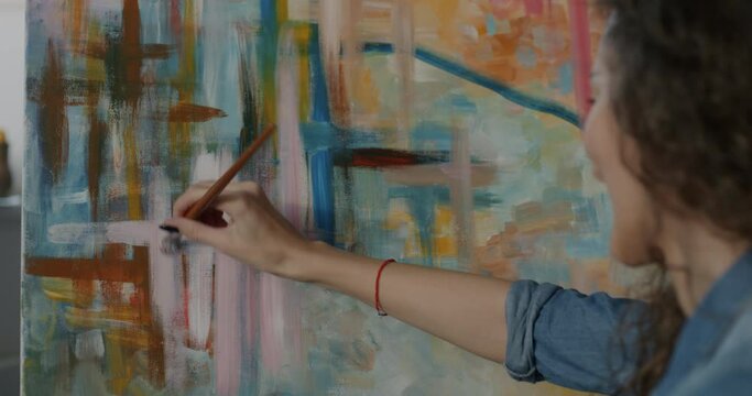 Talented modern artist painting multicolor abstract picture focused on creation of masterpiece in workshop. Creative job and people concept.