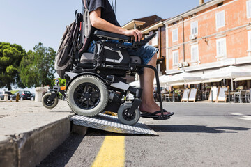 Male tourist on wheelchair crossing over the threshold ramp on the seaside promenade. Disability...