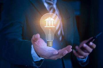Businessman hand holding virtual light bulb with banking icons. Financial innovation technology....