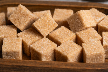 Cubes cane sugar in wooden bowl in closeup.