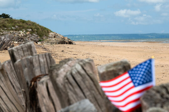 Utah Beach WWII  with Flag of USA selective focus on beach and ocean. Sandy beach and fence posts. Normandy France rememberance of Veterans Day. High quality photo