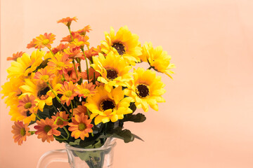 Bouquet yellow flowers in jug on pink background.
