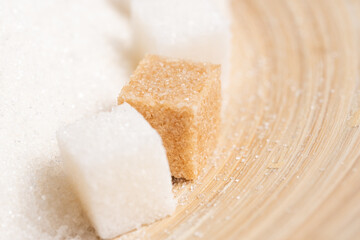 Granulated sugar and refined cane on a wooden background.