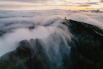 Aerial view of majestic mountain ridges at sunrise with falling fog from top of Pico do Areeiro, Madeira island, Portugal