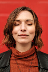 Relaxed woman with eyes closed in front of red background.