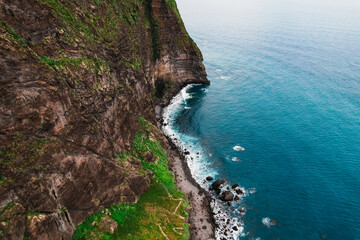Aerial view of rough ocean with waves, volcanic beach in Porto da Cruz, Madeira, Portugal
