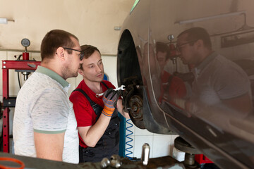 The repairman tells the client the reasons for the breakdown in the car. service center, car...