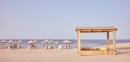 Retro toned photo of a beach with beach gazebo, sun loungers and umbrellas, Egypt.