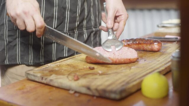 Parrillero, chef, corta un chorizo en la tabla en slowmotion. 