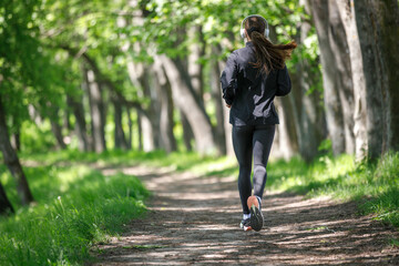 Young fitness woman jogging in park at sunny morning