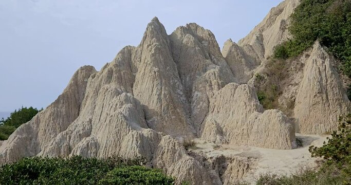 White Sandstone Mountains on the Gerakas Beach on the southern coast of Zakynthos, clay rock formations overgrown with bushes, Greece.