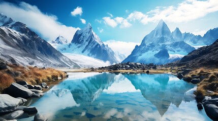 Mountain landscape with a crystal-clear lake reflecting snowy peaks under a blue sky